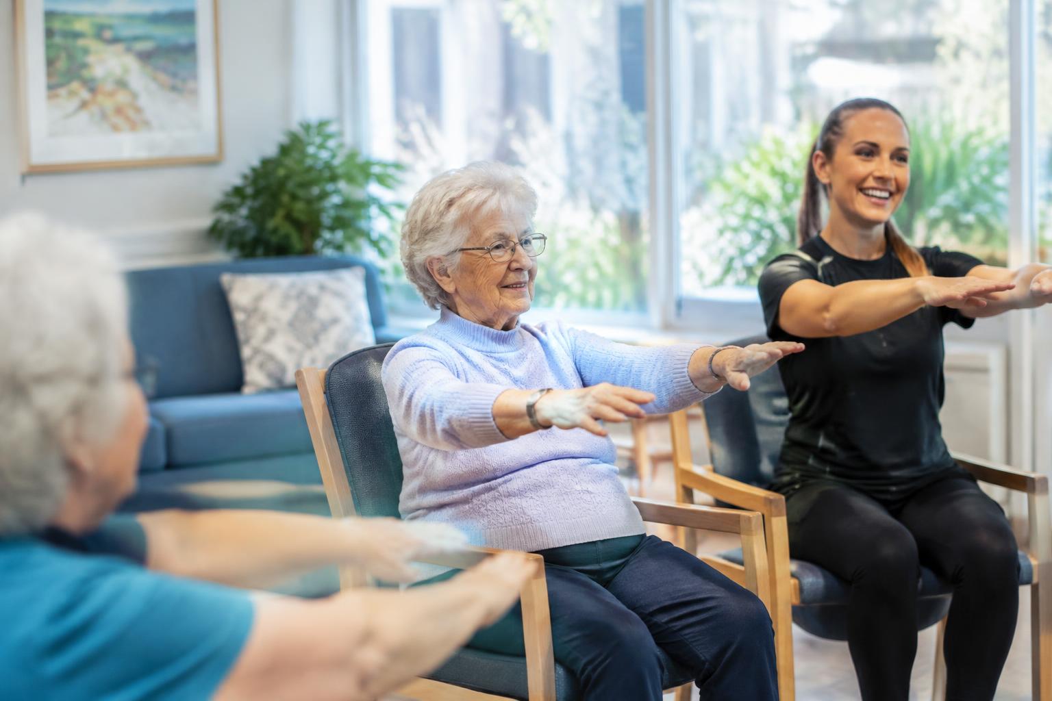 Older residents taking part in a seated movement session with a facilitator